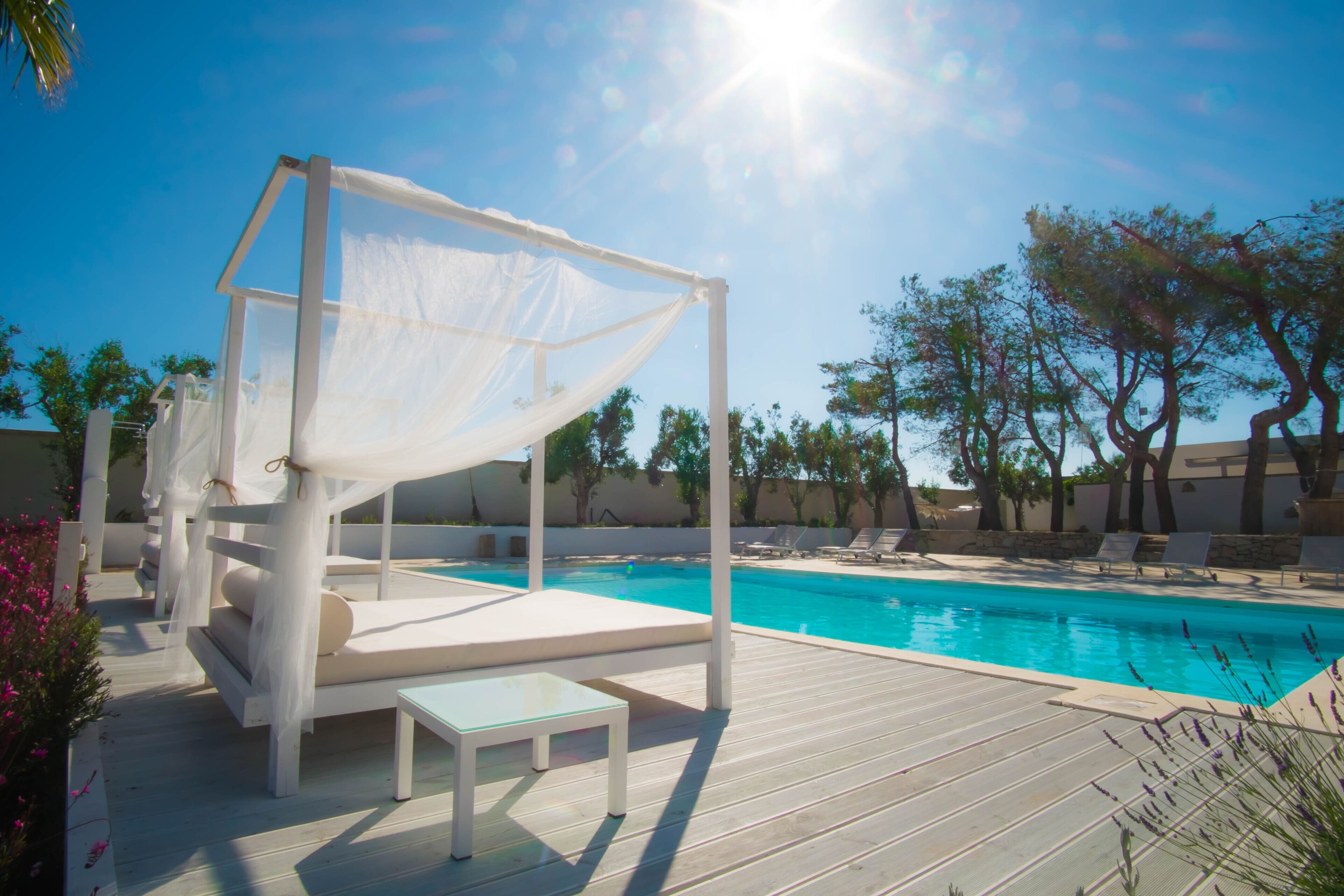 Ein Poolbereich mit weißem Baldachin, Liegestühlen und einem Pool.