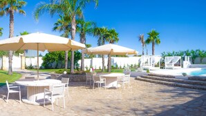 Un espace aménagé au bord de la piscine, avec des chaises longues, des parasols et une terrasse en pierre.