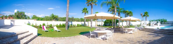 Un espace aménagé au bord de la piscine, avec des chaises longues, des parasols et une terrasse en pierre.