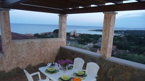 A table set for two with white chairs, a view of the sea, and a stone wall. - Very panoramic 10 minutes walk from the sea (Villaputzu)