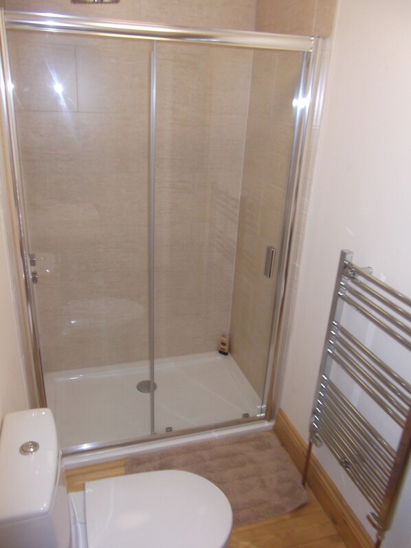 A bathroom with a glass-enclosed shower, a toilet, and a towel rack. - Courtyard Cottage, Great Paxton, St Neots, Cambs, PE19 6RA (Great Paxton)