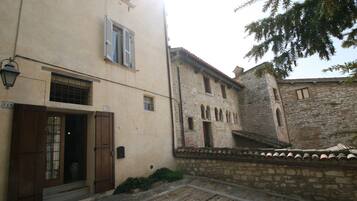 A courtyard with a stone wall, a wooden door, and a small table with a plant.
