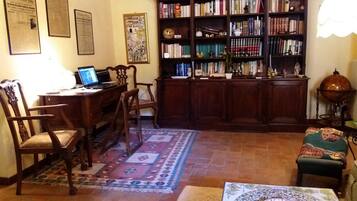 Un salon chaleureux avec un bureau en bois, une bibliothèque remplie de livres, un tapis à motifs et un globe terrestre décoratif.