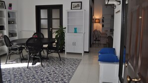 Zona pranzo con tavolo rotondo, sedie nere, mobiletto bianco e tappeto azzurro con motivo.