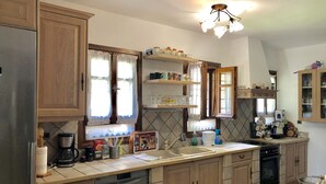 A kitchen with wooden cabinets, a dishwasher, a coffee maker, and a sink. - Villa Maira, Chalkidiki. Holidays as it should be! (Afytos Kassandras Chalkidiki)