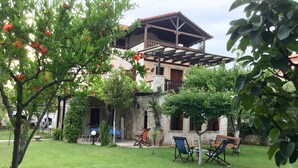 A house with a patio area, outdoor seating, and a garden. - Villa Maira, Chalkidiki. Holidays as it should be! (Afytos Kassandras Chalkidiki)