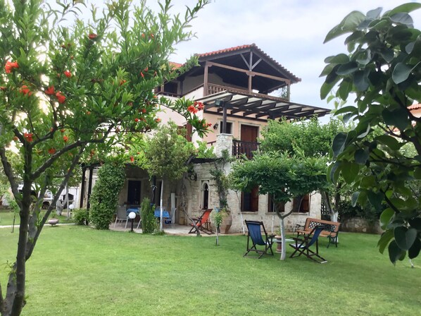 A house with a patio area, outdoor seating, and a garden. - Villa Maira, Chalkidiki. Holidays as it should be! (Afytos Kassandras Chalkidiki)