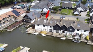 A riverside building with a dock, surrounded by residential houses and parked cars. - Self Catering 3 Bedroom Sunset  Haven In Wroxham, Norfolk, Norfolk Broads, Eng (Wroxham)