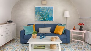 Ein modernes Wohnzimmer mit einem blauen Sofa, einem weißen Couchtisch und einem Baumgemälde.