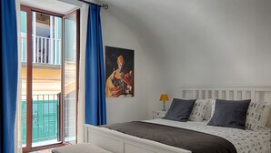 Ein Schlafzimmer mit einem Bett, einer Bank, einem Nachttisch, einer Lampe und einem Gemälde.