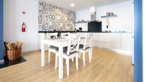 Eine moderne Küche mit weißen Schränken, einer gemusterten Spritzschutzwand und einem Essbereich mit weißem Tisch und Stühlen.