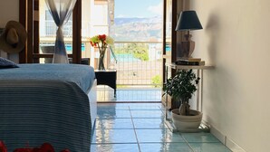 Un dormitorio con cama, una planta en maceta, una lámpara y vistas al balcón exterior.