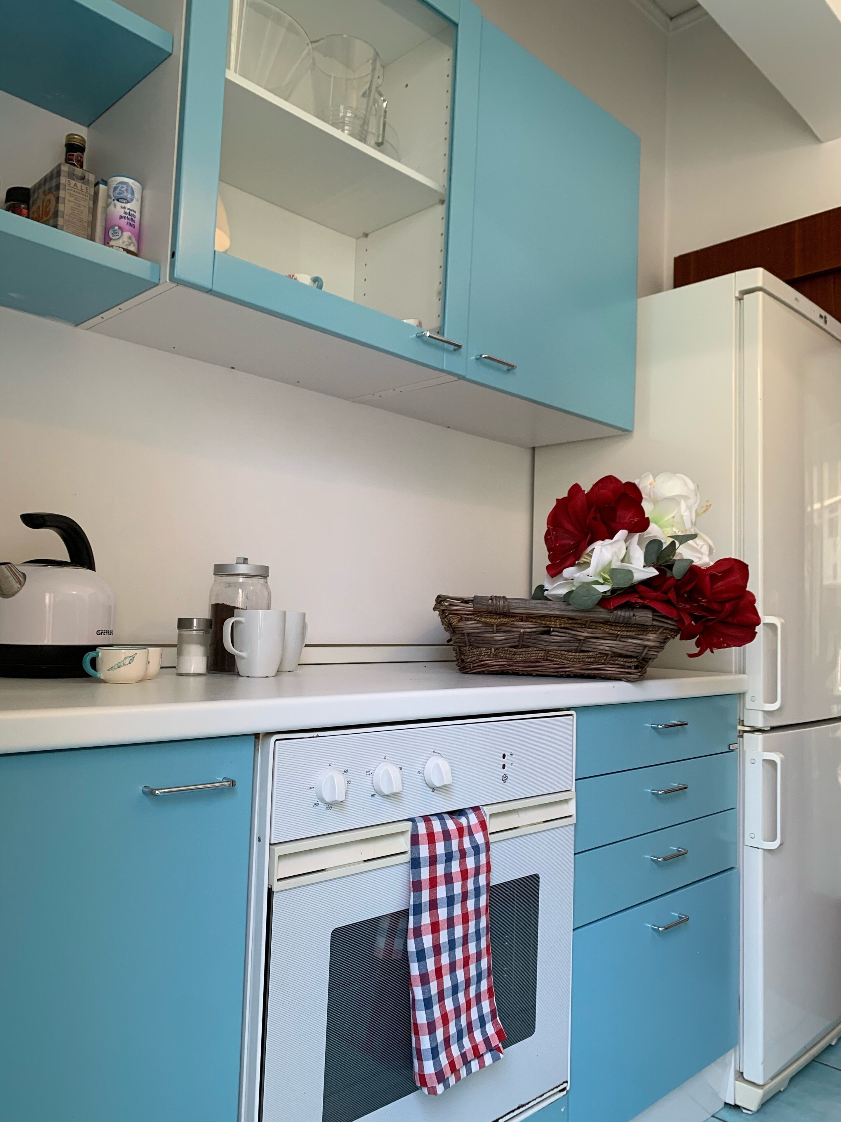 Una cocina con armarios azules, una estufa blanca y un refrigerador.