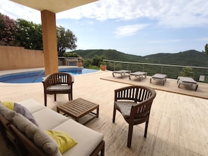 Ein Poolbereich mit Liegestühlen, einem Holztisch und einer Couch.