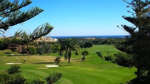 A golf course with a view of the ocean and a building in the background.