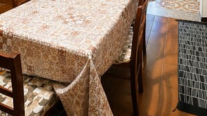 A dining area with a table, chairs, and a kitchen area with cabinets and a coffee machine. - Giba holiday home near the sea (Giba)