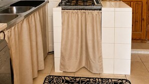 A kitchen with a gas stove, stainless steel sink, and a wooden cabinet. - Giba holiday home near the sea (Giba)