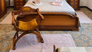 A bedroom with a large wooden bed, two nightstands, a wooden chair, a chandelier, and a framed picture on the wall. - Giba holiday home near the sea (Giba)