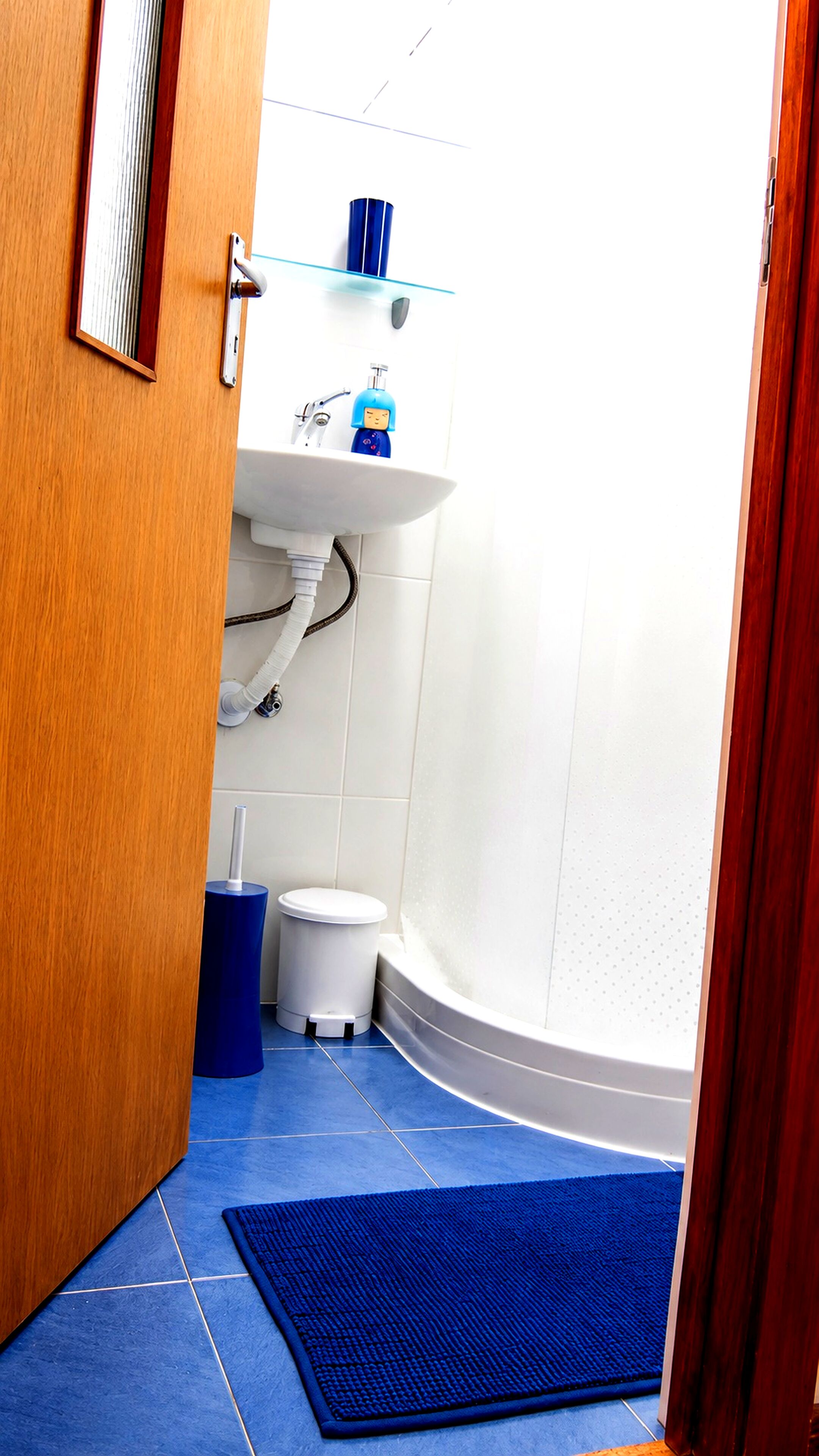A bathroom with a toilet, sink, and blue mat.