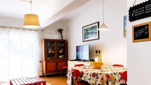 Een eetgedeelte met een tafel voor vier personen, een televisie en een kast met glazen deuren.