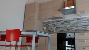 Une cuisine moderne avec des meubles en bois, un four encastré et une table à manger rouge avec des chaises.