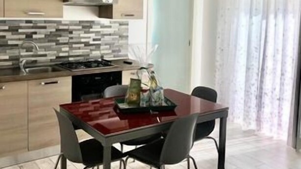 Une cuisine moderne avec une table à manger rouge, des chaises grises et un lustre.
