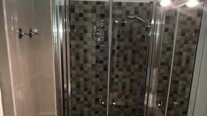 Une salle de bain moderne avec une douche à parois de verre, un lavabo blanc et des murs carrelés.