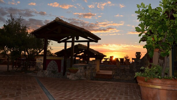 A gazebo with stone walls and a tiled patio.