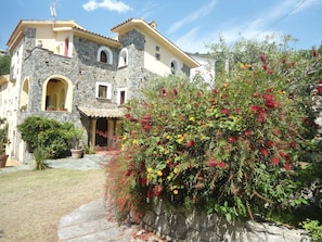 Uma casa de pedra de dois andares com fachada amarela e entrada de pedra.