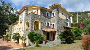A two-story stone building with a yellow facade, multiple windows, and a stone entrance.