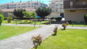 A residential area with a paved walkway, green lawns, and a row of multi-story buildings with balconies. - Residential tourist use with WiFi (Villarcayo)