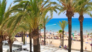 Escena de playa con palmeras, arena dorada y cielo azul despejado.