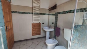 Ein Badezimmer mit Toilette, Bidet, Waschbecken und einer Holztür.