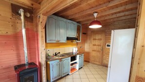 Eine kleine Küche mit Holzwänden, einem Herd, Schränken und einem Kühlschrank.