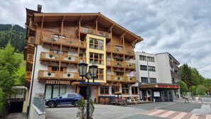 A multi-story wooden building with balconies, a restaurant, and a car parked in front.