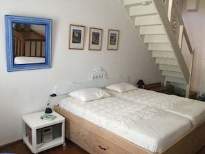 Une chambre à coucher avec un lit, une table de chevet, un miroir et un escalier.