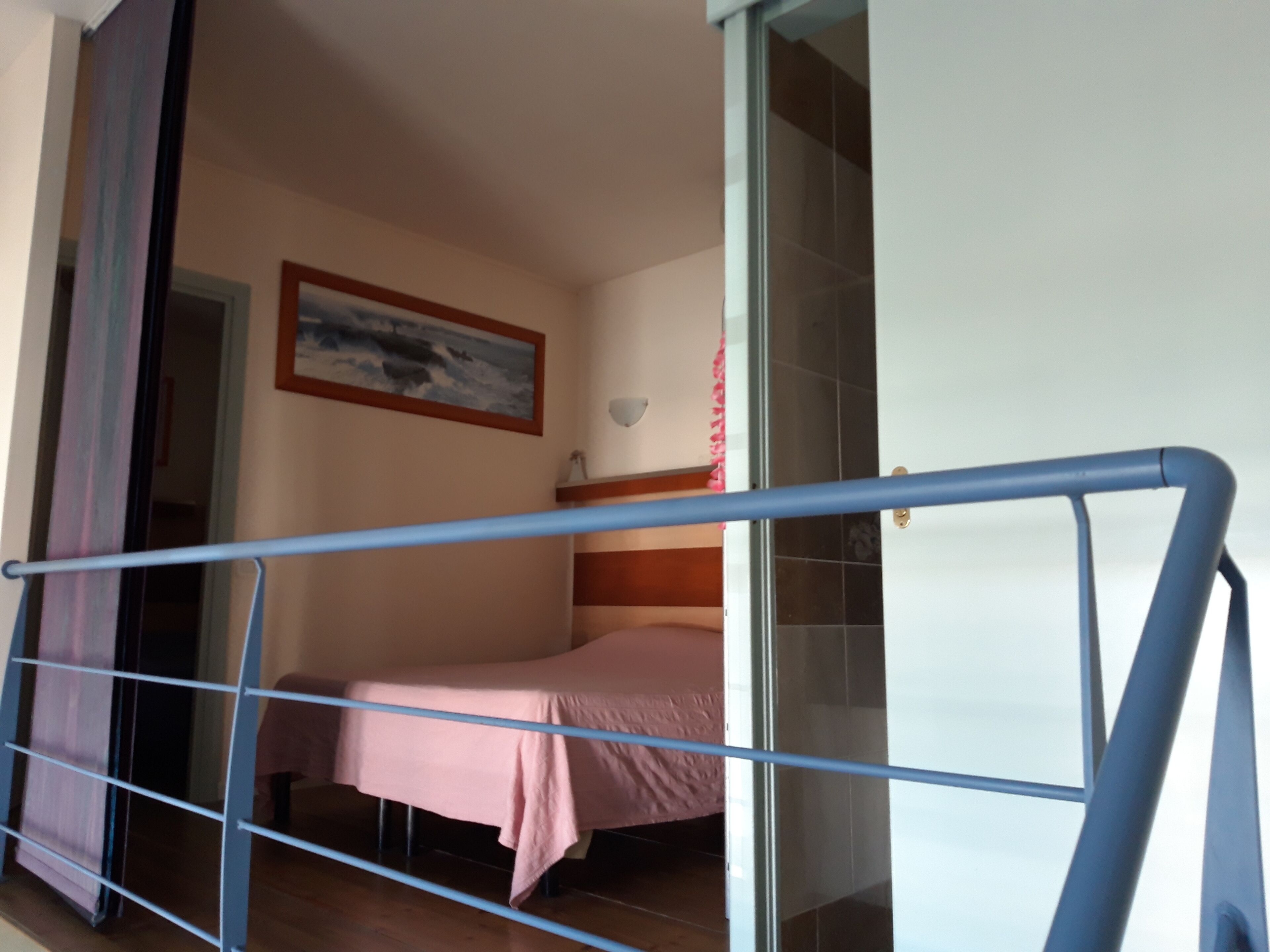 Une chambre à coucher avec un lit, un tableau accroché au mur et une fenêtre avec des rideaux.