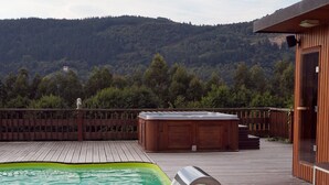 Eine Holzterrasse mit Whirlpool und Schwimmbad.