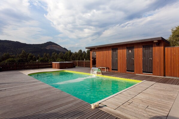 Une terrasse en bois avec une piscine et un sauna.