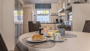 A modern kitchen with a dining table set for breakfast, featuring a croissant, eggs, and coffee. - Generous and tasteful: This terraced house of about (Carolinensiel)