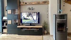 A modern living room with a flat-screen TV, wooden shelving, and a built-in fireplace. - Generous and tasteful: This terraced house of about (Carolinensiel)