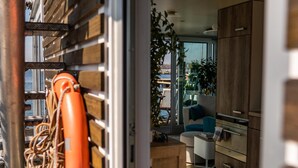 A modern kitchen with wooden cabinets, a white countertop, and a blue chair. - Houseboat Canoga in Labo marina (Laboe)