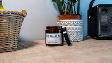 Um frasco de Laboe, Wellen & Meer Sojawachscherze sobre uma mesa com uma cesta de vime e uma planta em vaso ao fundo.
