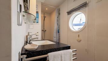 Een badkamer met een wastafel, spiegel, douche en een raam met uitzicht.