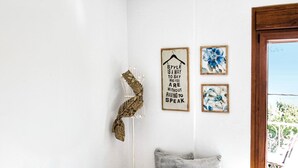 A bedroom with a bed, a hanging light, a floor lamp, and artwork on the wall. - Asprolithos Studios (Skiathos)