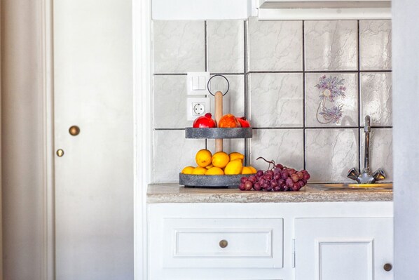 Una cocina con una exposición de frutas en la encimera, una planta en maceta y una puerta blanca.
