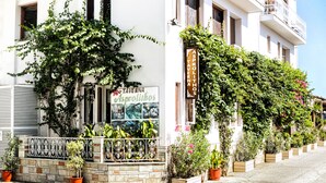 A building with a sign reading "ASPROLITHO TAVERNA Asprolithos" and a balcony with potted plants. - Asprolithos Studios (Skiathos)