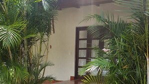 A set of stone steps leading to a door with a window, surrounded by lush greenery and potted plants. - Beautiful country house in the magical town of Malinalco (Malinalco)