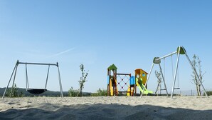 Un parque infantil con columpios y estructuras para escalar en una playa de arena.