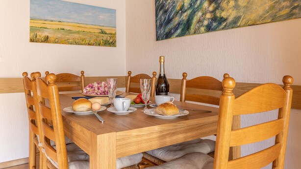 Una mesa de madera con sillas, una botella de vino y platos de comida.